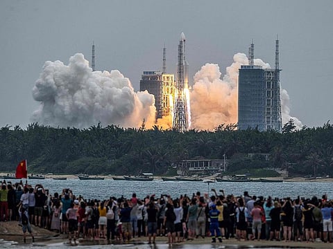 People watch a Long March 5B rocket, carrying China's Tianhe space station core module, as it lifts off from the Wenchang Space Launch Center in southern China's Hainan province on April 29, 2021. 