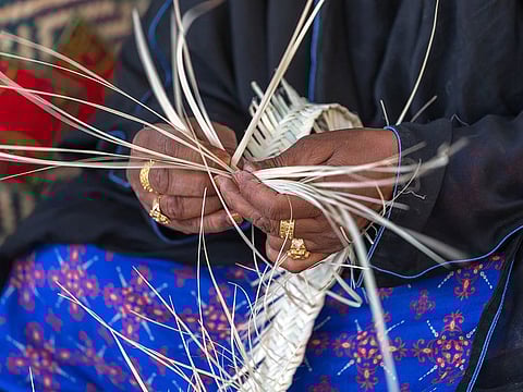 An Emirati woman is weaving traditional basket from palm leaves, the practice of which is called Safifa in Arabic. Picture used for illustrative purposes only.