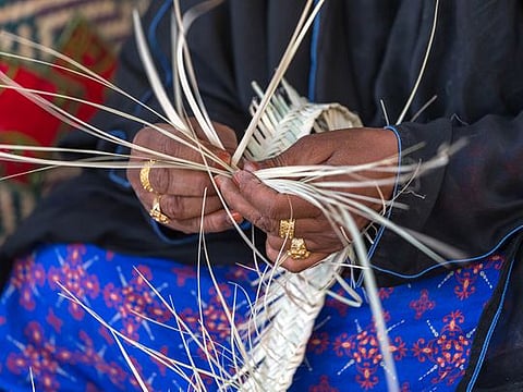 An Emirati woman is weaving traditional basket from palm leaves, the practice of which is called Safifa in Arabic. Picture used for illustrative purposes only.