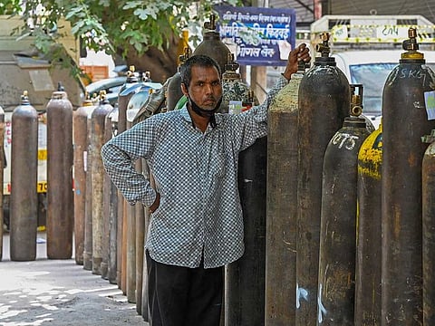 A man waits to refill his medical oxygen cylinder for a COVID-19 coronavirus patient under home quarantine at a private refill centre in New Delhi on May 4, 2021, as India's total COVID-19 caseload soared past 20 million. 