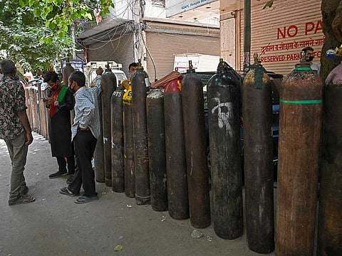 People wait to refill their medical oxygen cylinders for the COVID-19 coronavirus patients under home quarantine at a private refill centre in New Delhi on May 4, 2021, as India's total COVID-19 caseload soared past 20 million. 
