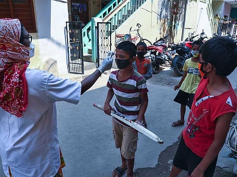 An Indian health worker checks body temperature of boys playing cricket in a lane during a door-to-door survey being conducted as a precaution against COVID-19 in Hyderabad, India, Thursday, May 6, 2021. 