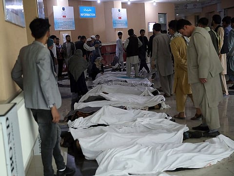 Men try to identify the dead bodies at a hospital after a bomb explosion near a school west of Kabul, on Saturday, May 8, 2021. 