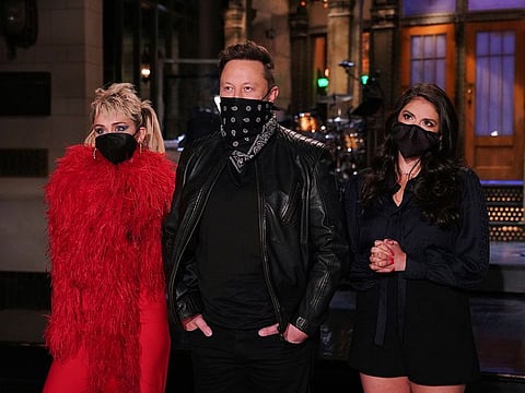This image released by NBC shows musical guest Miley Cyrus, from left, host Elon Musk, and Cecily Strong during promos in Studio 8H on Thursday, May 6, 2021.