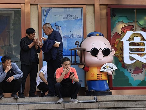 Residents smoke along the popular Wangfujing shopping district in Beijing Tuesday, May 11, 2021. The number of working-age people in China fell over the past decade as its aging population barely grew, a census showed Tuesday, adding to economic challenges for Chinese leaders who have ambitious strategic goals. 
