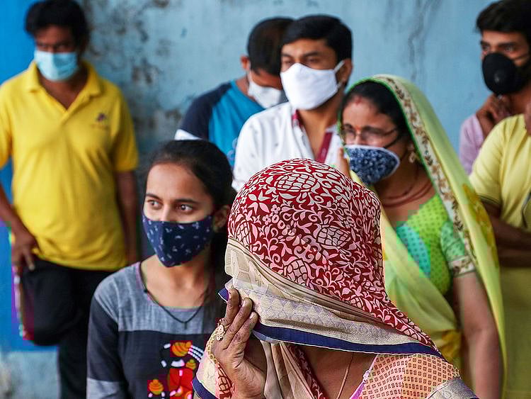 People wearing masks wait to test for COVID-19 at a hospital in Hyderabad. 