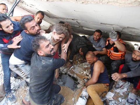 Rescuers carry a girl as they search for victims amid rubble at the site of Israeli air strikes, in Gaza City.