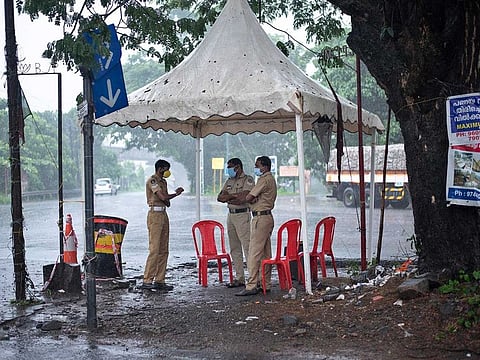 Policemen enforcing a lockdown to curb the spread of coronavirus stand beneath a rain shelter in Kochi, Kerala state, India, Sunday, May 16, 2021. A severe cyclone is roaring in the Arabian Sea off southwestern India with winds of up to 140 km  per hour, already causing heavy rains and flooding that have killed at least four people, officials said Sunday. 