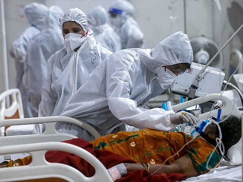 In this May 6, 2021, file photo, a health worker tries to adjust the oxygen mask of a patient at the BKC jumbo field hospital, one of the largest COVID-19 facilities in Mumbai, India. 