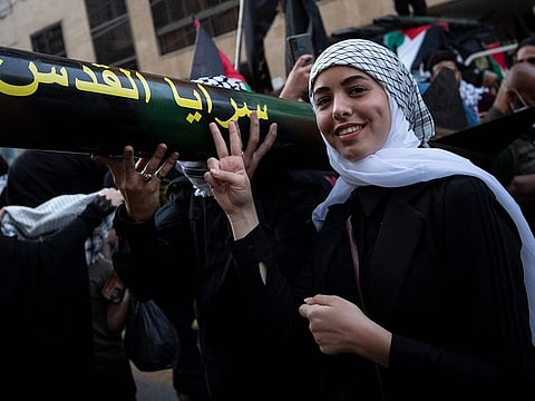 A girl poses for a photograph next to a replica rocket, during a rally organized by Lebanon's militant Hezbollah group, in the southern suburb of Beirut, Lebanon, Monday, May 17, 2021. 