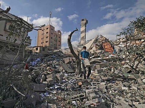 A Palestinian youth amid the rubbe of the Kuhail building which was destroyed in an early morning Israeli airstrike on Gaza City on May 18, 2021