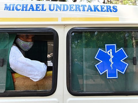 This picture taken on May 8, 2021 shows a man looking out of a Michael Undertakers and Ambulance Services vehicle while preparing to transport a coffin bearing the body of a coronavirus victim, outside a hospital mortuary in New Delhi. As India grapples with a mounting coronavirus death toll, new services ranging from specialist funeral firms, Bollywood film set cleaners and low-budget deliverymen are easing the pain and making a living. 