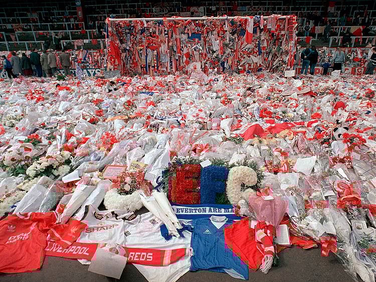 Thousands visited Anfield Stadium to pay their respects as flower tributes cover the 'Kop' end of the field, in Liverpool, on April 17, 1989, following April 15, when fans surged forward during the FA Cup semi-final between Liverpool and Nottingham Forest at Hillsborough Stadium in Sheffield, when the crash barriers gave way, killing 96 Liverpool fans and injuring over 200 others.