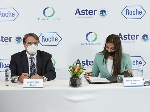 Harald Wolf of Roche (left) and Alisha Moopen of Aster sign the agreement.
