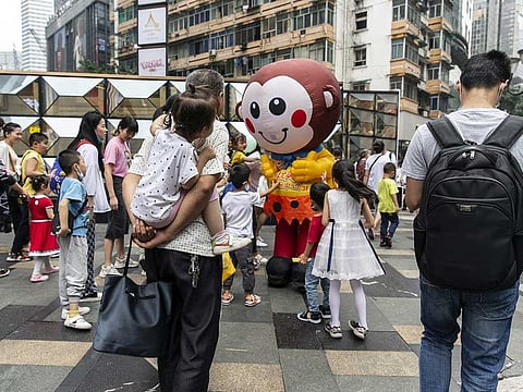 Children interact with a person dressed as a mascot in Chongqing, China, on Tuesday, June 1, 2021. 