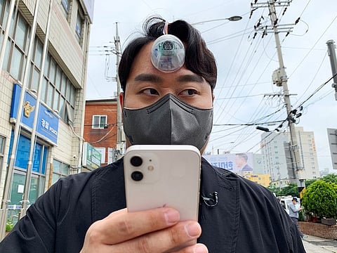 Designer Paeng Min-wook showcases a robotic eye, called "The Third Eye", on his forehead as he uses his mobile phone while walking on street, in Seoul. 