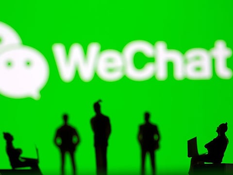 Small toy figures are seen in front of WeChat logo in this illustration. 
