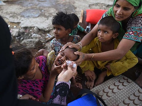 A health worker administers polio vaccine drops to a child during a polio vaccination campaign at a slum area in Karachi on June 7, 2021. 