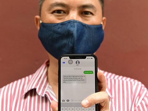 Civil servant Nguyen Tuan Anh poses with his smartphone displaying a message acknowledging his donation to Vietnam’s national fund for COVID-19 vaccine in Hanoi on June 8, 2021, as a response to the government's public appeal for financial assistance while the country struggles to contain a new coronavirus wave.