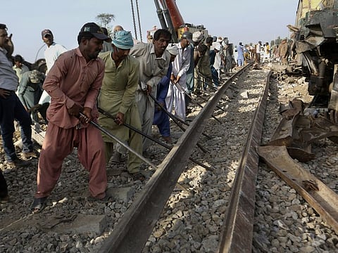 Railway workers rebuild the track at the site of a train collision in the Ghotki district, southern Pakistan, on Tuesday.  