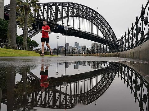 A runner exercises in wet conditions under the Sydney Harbour Bridge as eastern Australia experiences a winter cold front, in Sydney, Australia, June 10, 2021.  