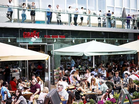 People sit at an outdoor restaurant on the South Bank during sunny weather, in London, on June 5, 2021. 