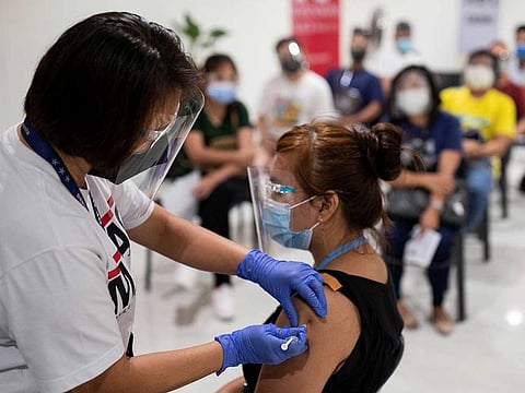 A health worker administers a dose of the Russian Sputnik V COVID-19 vaccine, as workers queue to get vaccinated at Robinsons Place, in Manila, Philippines, June 8, 2021. 