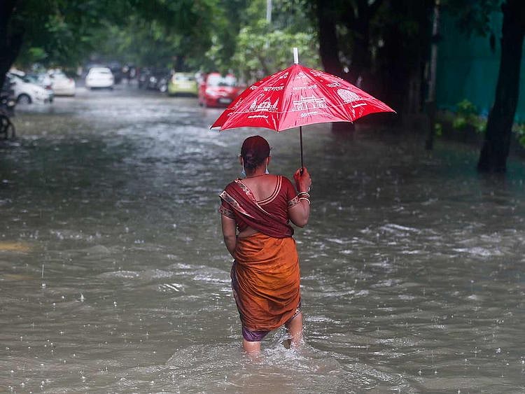 A woman walks through a flooded street during heavy rains in Mumbai