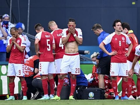 Denmark players react while medics assist Christian Eriksen after he collapsed on the pitch during the Euro 2020 match against Finland 