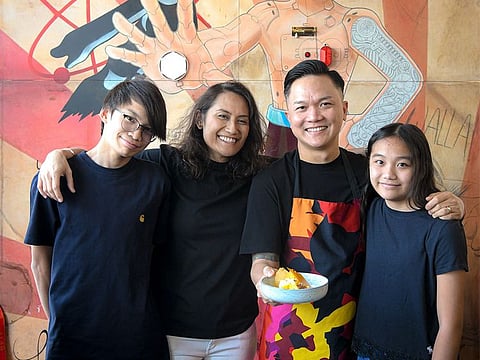 Reif Othman and his family standing inside his neighbourhood restaurant celebrating their 10-year Golden Visa. 