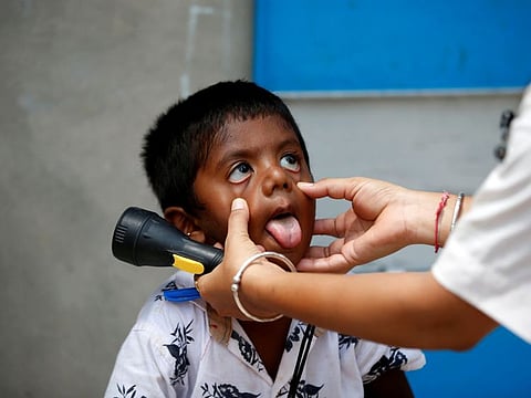 A healthcare worker examines a child during a door-to-door surveillance to safeguard children amidst the spread of the coronavirus disease (COVID-19), at a village on the outskirts of Ahmedabad, India on June 9, 2021.  Experts said children faced greater threat during the third COVID-19 wave.