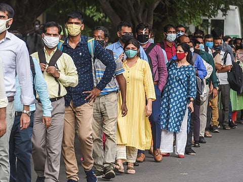 People stand in a queue outside the Barakhamba metro station after resumption of the metro services in a graded manner in New Delhi.
