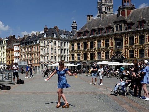 A woman dances by a cafe terrace in Lille, northern France. France is lifting mandatory mask-wearing outdoors and will halt an eight-month nightly coronavirus curfew on June 20. 