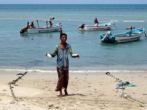 A Yemeni fisherman smiles as he carries squid upon return from a fishing trip off the coast of the Red Sea city of Hodeida, on April 5, 2021. Abdul Hakeem related how he was among 35 fishermen who stumbled upon a floating sperm whale carcass , about 26km off the coast of the southern city of Aden. 