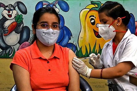 A health worker inoculates a woman in New Delhi on June 21, 2021 after India opened up free vaccination to all adults in an attempt to bolster its inoculation drive.  