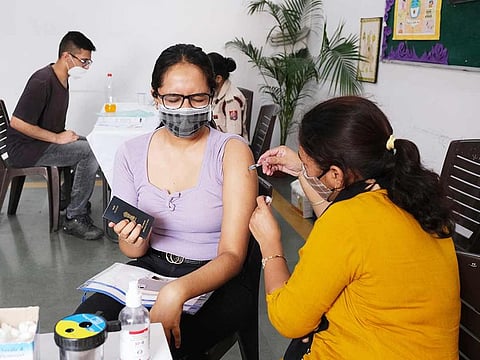 A health worker administers a dose of the Covishield vaccine to a student, at a COVID-19 vaccination center set up in a school in New Delhi. 