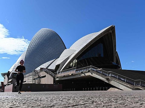 A woman runs past the Opera House in Sydney on June 26, 2021, after authorities locked down several central areas of Australia's largest city to contain an outbreak of the highly contagious Delta variant. 