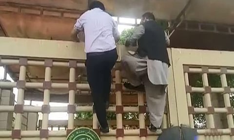Opposition legislators scaling Sindh Assembly gates to attend the session.