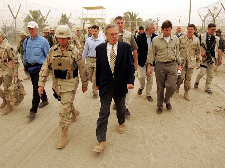 In this file photo taken on May 13, 2004 US Defence Secretary Donald Rumsfeld and Major General Geoffrey Miller (left), Deputy Director of detainee operations walk the grounds of the Abu Ghraib Prison, 30 kms west of Baghdad. Rumsfeld, who led the nation into war in Afghanistan and Iraq during the presidency of George W Bush, died at the age of 88 in New Mexico, his family announced June 30, 2021.
