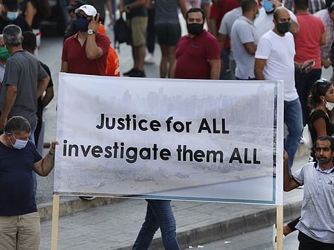 In this Aug. 31, 2020 file photo, Lebanese supporters of President Michel Aoun hold a banner during a protest calling for "truth and justice" in relation to the August 4 explosion that devastated Beirut port and parts of the Lebanese capital.