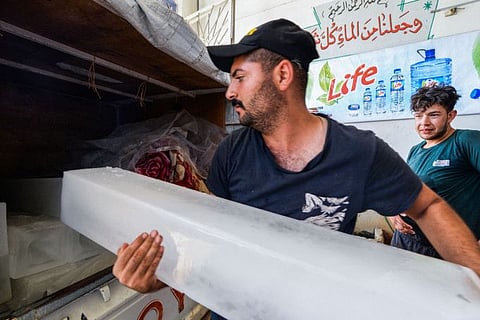 An Iraqi worker loads ice blocks into a customer's pick-up truck at a factory in the northern city of Mosul, on July 3, 2021, amid power outages and soaring temperatures. Anger has mounted among Iraq's 40-million population, with corrupt politicians at the centre of a blame game for its poor services and dilapidated infrastructure. Four southern provinces have been without electricity since June 29, and sizzling temperatures have been compounded by high levels of humidity. 