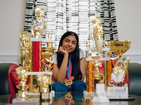 Ashrita Gandhari, 14, a finalist in the Scripps National Spelling Bee, poses for a portrait with her spelling bee trophies at her home in Ashburn, Virginia, on June 29, 2021. The bee has become an occasion for unity within the South Asian American immigrant community, and it all goes back to a historic victory more than three decades ago.