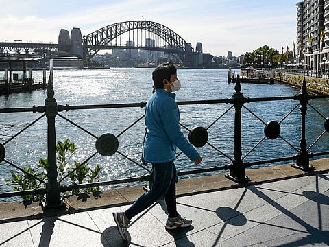 A woman wearing a face mask walks along a quiet Circular Quay in Sydney on July 6, 2021. 