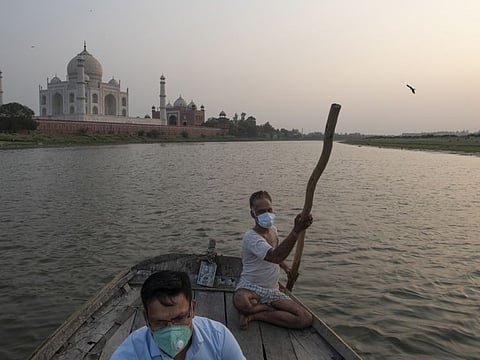Sumit Chaurasia, left, a guide at the Taj Mahal, in front of the monument in Agra, India, June 23, 2021, while on the Yamuna river. While the Taj Mahal partially reopened in mid-June — with strict limits on the number of visitors — Chaurasia’s life, like much of India, remains in limbo: no longer totally shut down, but far from fully normal or safe. 
