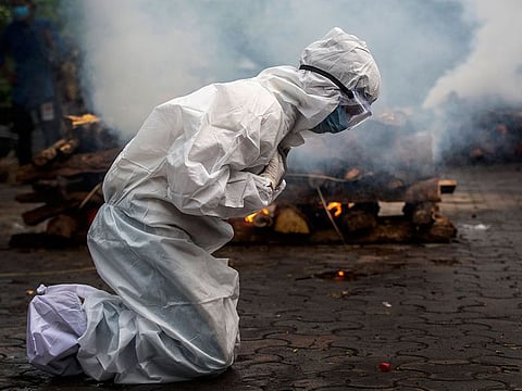A woman breaks down as she prays before the cremation of a relative who died of COVID-19 in Gauhati, India.