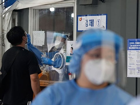 A medical worker in a booth takes a nasal sample from a man during a COVID-19 testing at its testing site in Seoul, South Korea, Thursday, July 8, 2021.