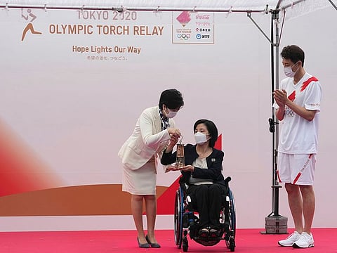 Tokyo Governor Yuriko Koike, left, receives a lantern containing the Olympic Flame from Aki Taguchi, centre, official ambassador of the Tokyo 2020 Torch Relay, as former tennis player Shuzo Matsuoka, right, applauds during the unveiling ceremony for Olympic Flame of the Tokyo 2020 Olympic torch relay at Komazawa Olympic Park, Friday, July 9, 2021, in Tokyo.