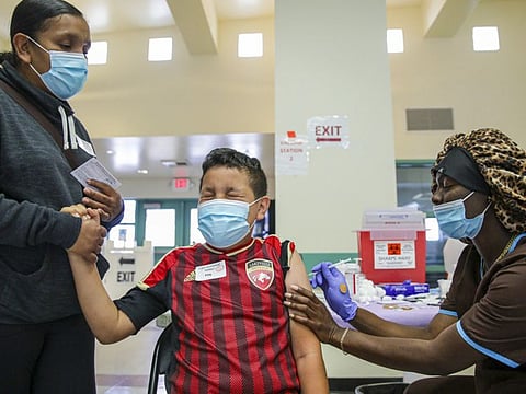 Christiana Neri, 38, holds her 13-year-old son Ivan Hernandez as Sequoia Hutton administers the Pfizer COVID-19 vaccine at a mobile vaccine clinic held for people age 12 and over at Roosevelt Park in Los Angeles. 