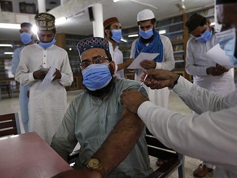 A student receives a vaccine from a health worker in an Islamic University ‘Jamia Naeemia’, in Lahore on July 12, 2021. 