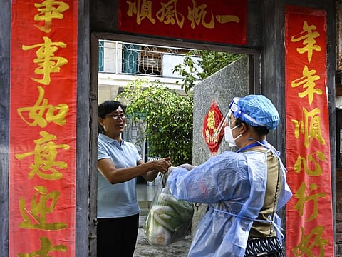 In this photo released by Xinhua News Agency, a community worker delivers daily necessities to a household under closed-off management in the city of Ruili in southwestern China's Yunnan Province on July 8, 2021. Chinese authorities locked down the city bordering Myanmar on Wednesday, shutting most businesses and requiring residents to stay at home as a fresh outbreak of COVID-19 expanded. 